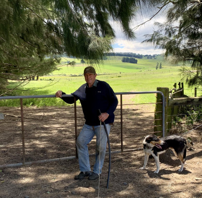 Farmer standing with his dog in front of his farm