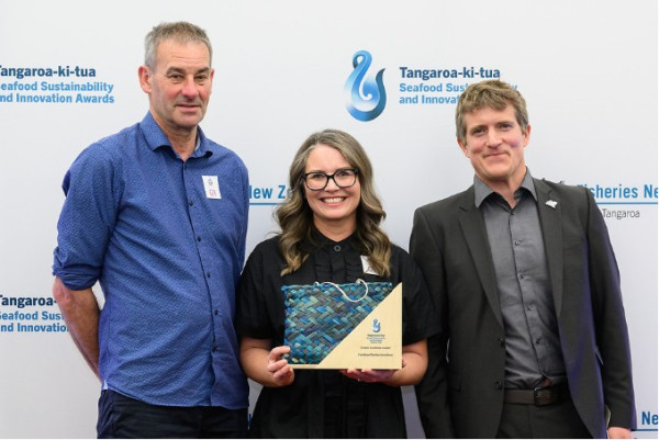 Three people holding an award.
