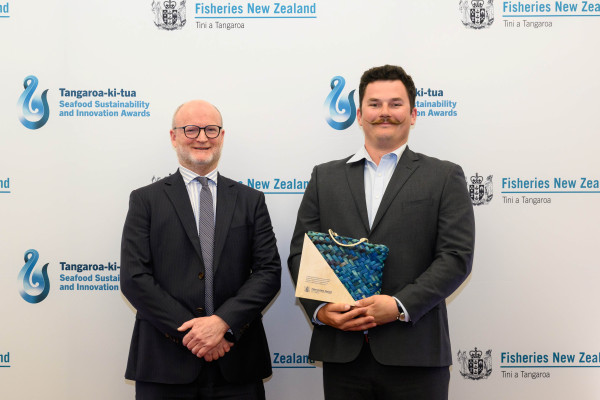 Two men in suit, holding an award.