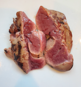 A partly cooked chicken liver, cut in half to show showing how red and raw it is on the inside.