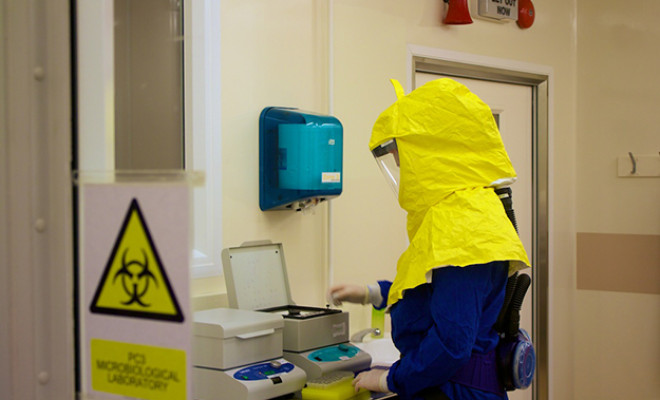Scientist in a biosecurity suit testing samples