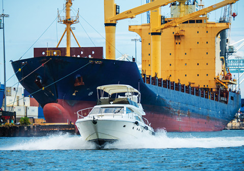 Boat speeding in front of a container ship