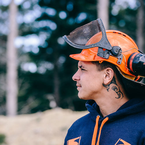 Young man in a helmet and high-vis clothing in a forest