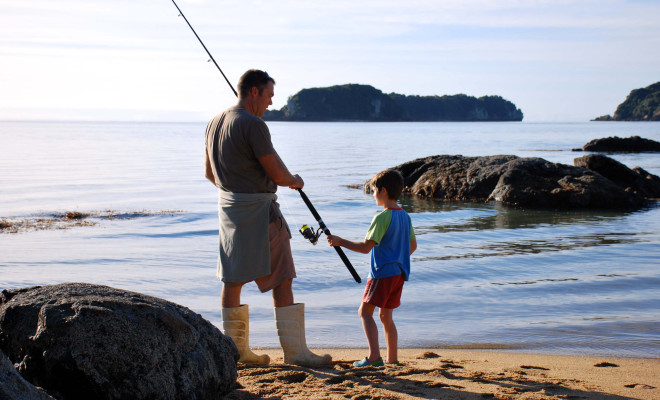 Man and child fishing on the beach.