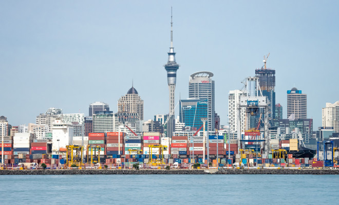 Auckland seaport: stacks of containers and skyscrappers in background.