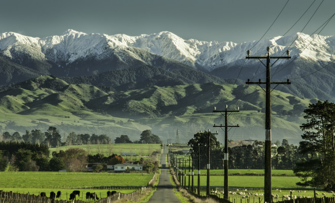 Farm road heading straight to the Southern Alps covered in snow.
